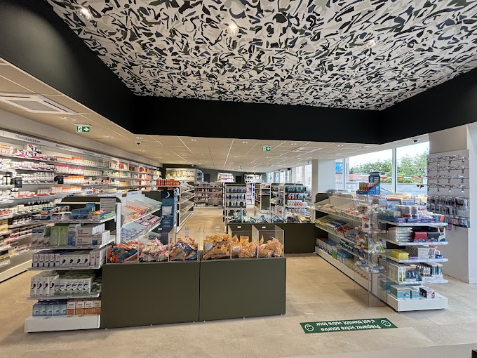 Intérieur de la pharmacie : rayonnages de parapharmacie et comptoirs, plafond à motifs noir et blanc